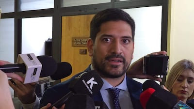 Mauricio Espínola en traje oscuro y corbata azul habla a periodistas, mientras un micrófono blanco asoma a la izquierda.