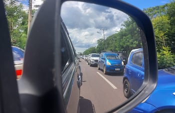 A través de un espejo retrovisor se observan a numerosos vehículos aguardando llegar al puesto de peaje de Ypacaraí. Están en el carril de salida en el sentido Ypacaraí-Caacupé.