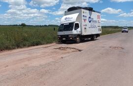 Un camión repartidor de mercaderías a punto de pasar un enorme bache del ramal.