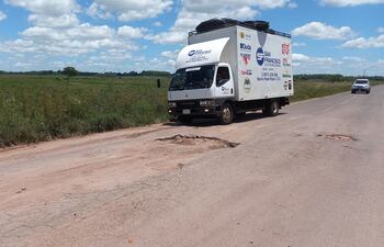 Un camión repartidor de mercaderías a punto de pasar un enorme bache del ramal.