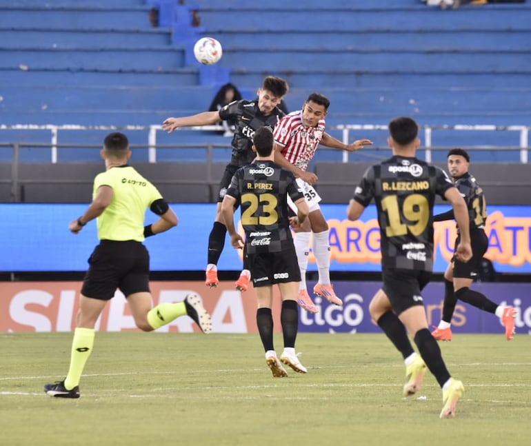 El zaguero de Olimpia, Juan Ángel Vera va a la disputa aérea con el delantero del Sportivo San Lorenzo, Cristhian Colmán.