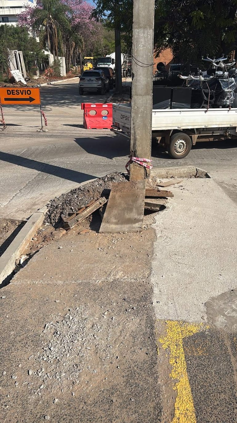 Ambiente urbano en construcción con un cartel naranja de desvío y vehículos estacionados cerca de la obra.