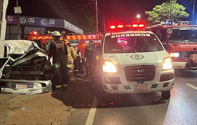 Bomberos y paramédicos en uniforme trabajan alrededor de un vehículo dañado.