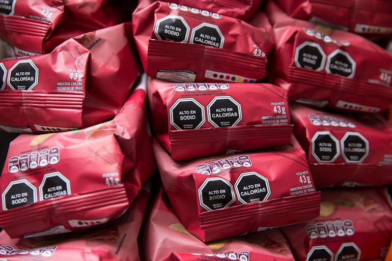 Una pared repleta de paquetes de papas fritas con sellos de advertencia alimentaria en un puesto callejero en Santiago (Chile).
