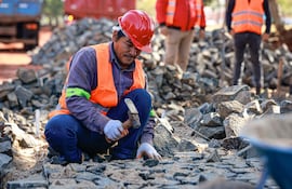 En primer plano, un obrero trabaja en la colocación de empedrado en Hernandarias, como parte del “Plan 1000” que contempla 1.000 km de caminos en los 17 departamentos y la capital.