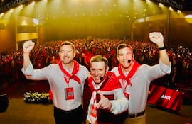 Santiago Peña y Pedro Alliana en camisas blancas y pañuelos rojos, levantando los brazos en un evento con multitud de personas vistiendo rojo.