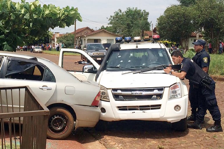 Policías parapetados detrás de su patrullera acribillada, durante el asalto con toma de rehenes en Santa Rita, el 19 de noviembre de 2014.