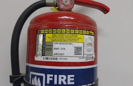Extintor de incendios rojo con etiqueta amarilla de verificación, fondo blanco sin personas visibles.