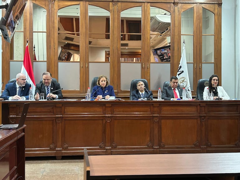 Diego Crispín Candia Melgarejo y Alicia Pucheta en reunión formal, vestidos de traje, rodeados de banderas y ambiente institucional.