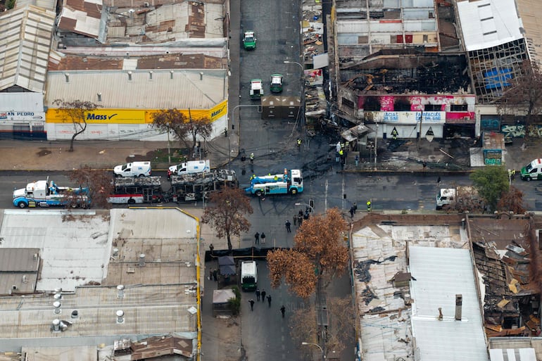 Vista aérea tras la colisión de una furgoneta con un autobús de la Red Metropolitana de Movilidad (RED) en el barrio Franklin, Santiago, Chile. Cinco personas fallecieron en el accidente entre una furgoneta y un autobús, el cual provocó un incendio que envolvió al vehículo de transporte público y a locales comerciales.