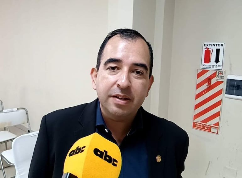 Arnaldo Valdez de pie en conferencia, con camisa azul y saco negro, sosteniendo un micrófono en un ambiente de reunión.