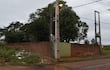 Entorno urbano con dos postes eléctricos, montículo de basura y pared de ladrillo en una calle descuidada.