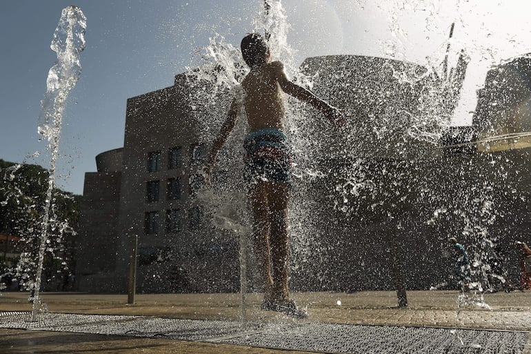 Un joven se refresca en una fuente frente al Museo Guggenheim Bilbao este martes en que Euskadi afronta la segunda jornada en alarma roja por temperaturas extremas, que se espera que ronden los 40 grados en todo el territorio.