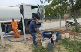Desde un camión cisterna descargan el agua cruda tomada del río Paraguay para las familias de Carmelo Peralta, donde no logran solucionar la falta de sistema de suministro de agua potable.