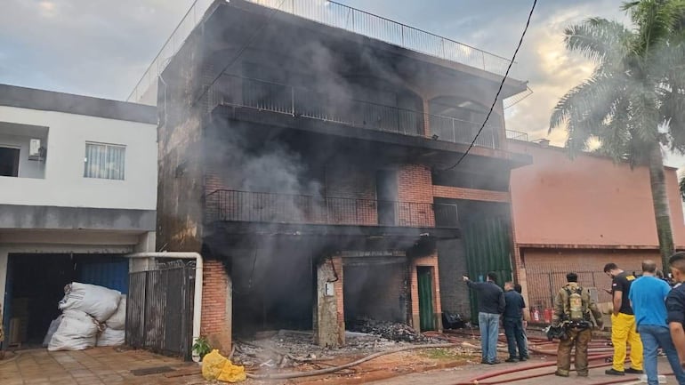 Grupo de diez personas, algunos en uniforme de bombero, luchando contra el fuego en un edificio afectado por un incendio.