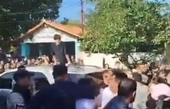 Policías toman del cuello a un hombre en medio de una gresca, en Alberdi, frente a un local de votación.