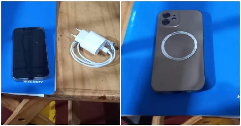 Dos teléfonos móviles, un modelo antiguo con grieta y otro más reciente, junto a un cargador en una mesa de madera.