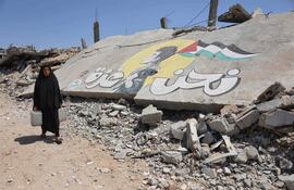 Una mujer camina llevando agua en el barrio Sheikh Radwan de la Ciudad de Gaza.