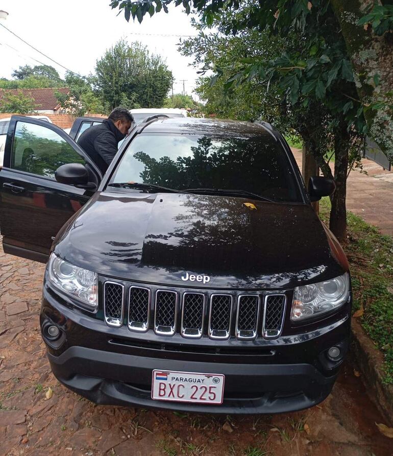 Un jeep negro estacionado en un área residencial con árboles y vereda visible, sin personas a la vista.