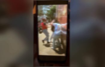 Madre de estudiante con expresión preocupada mientras sostiene documentos en un entorno escolar.