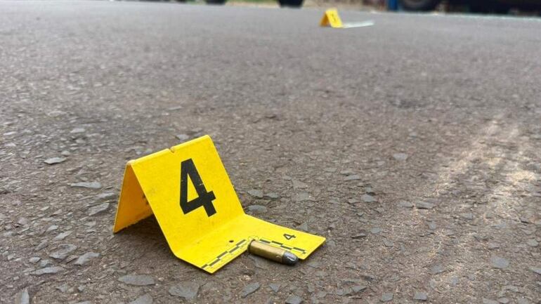 Marcadores amarillos con el número 4 en el suelo y una bala cerca, reflejan un ambiente de investigación policial.