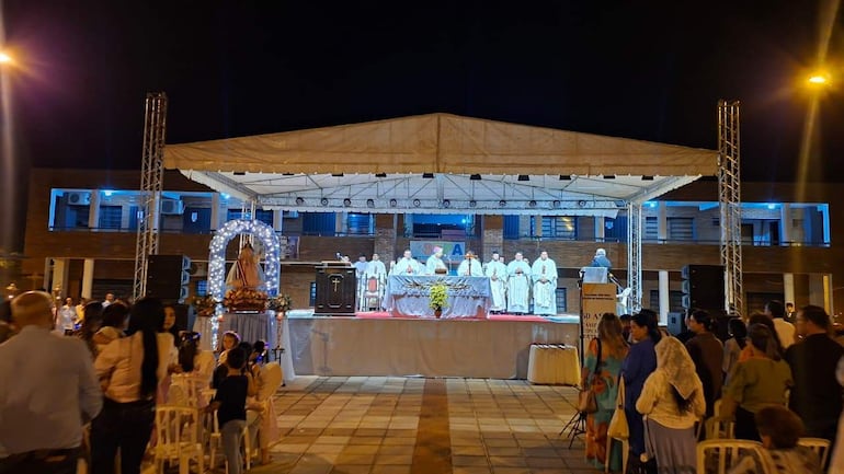 Monseñor Gavilán y varios religiosos en ceremonia, rodeados de fieles en un ambiente festivo, decoraciones y luces.