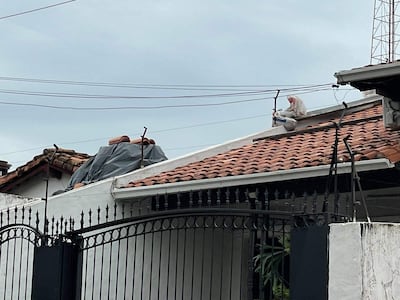 Montículo de escombros y cerámica en vereda junto a un árbol, con vehículos estacionados al fondo en un ambiente urbano.