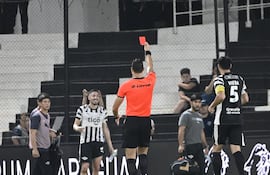 El árbitro David Ojeda exhibe la cuestionable tarjeta roja directa al mediocampista de Libertad, Álvaro Campuzano, en el clásico "blanco y negro" ante Olimpia.