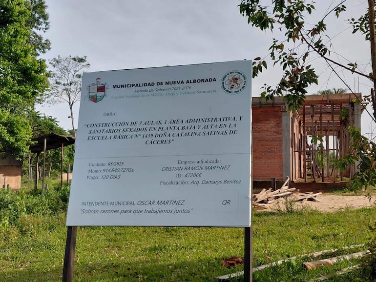 Cartel informativo de la Municipalidad de Nueva Alborada sobre la construcción en la Escuela Básica N° 1439, rodeado de vegetación y cielo despejado.