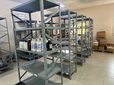 Estanterías metálicas vacías en un depósito, con cajas de cartón apiladas, reflejando el desabastecimiento de productos.