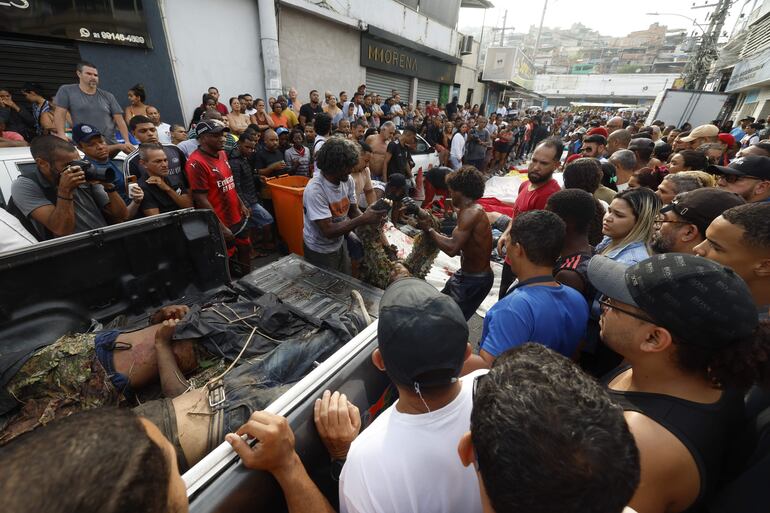 Personas observan cuerpos sin vida en un vehículo este miércoles, en Río de Janeiro (Brasil). 