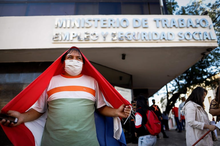 Un hombre posa con la bandera paraguaya en un acto conmemorativo por el Día del Trabajador frente a la sede del Ministerio del Trabajo.