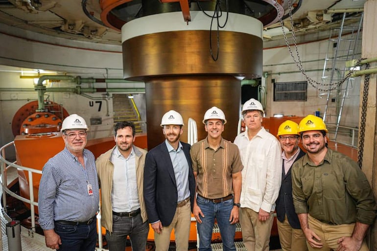 Santiago Peña con camisa azul claro y otros en casco, en ambiente industrial con equipos visibles de hidroeléctrica.