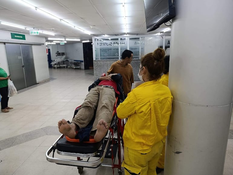 El cajero fue trasladado hasta el Hospital Central del IPS por Bomberos Voluntarios de Santísima Trinidad. En la imagen, una voluntaria lo traslada en camilla.