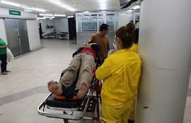 El cajero fue trasladado hasta el Hospital Central del IPS por Bomberos Voluntarios de Santísima Trinidad. En la imagen, una voluntaria lo traslada en camilla.