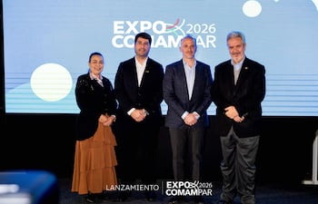 Cuatro personas posan sonrientes, vestidas formalmente, frente a fondo con el logo de la Expo 2026 COMAMPAR.