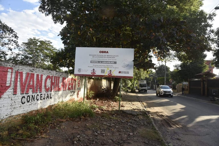 Mural que dice 'IVAN CHILAVERT CONCEJAL' junto a cartel de obra de desagüe pluvial y vegetación en Asunción.