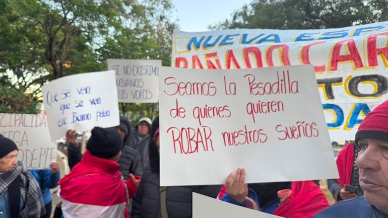 Manifestantes vestidos de abrigo sostienen carteles enérgicos, expresando su determinación en una jornada de protesta pacífica.