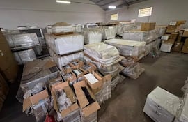 Almacén desordenado con estanterías llenas de cajas y productos envueltos en plástico, ambiente de almacenamiento activo.