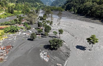 Una vista aérea muestra los restos de viviendas cubiertas de lodo mientras el agua turbia fluye por el río Budhi Gandaki, en el distrito de Gorkha, Nepal, el 14 de octubre de 2026, tras una inundación repentina provocada por un deslizamiento de tierra en seco.