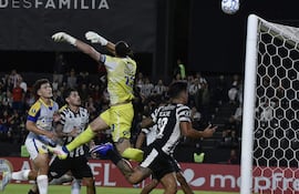 Jugadores de Libertad en camiseta blanca y Rosario Central en camiseta amarilla, en un campo de fútbol con un balón en el centro.