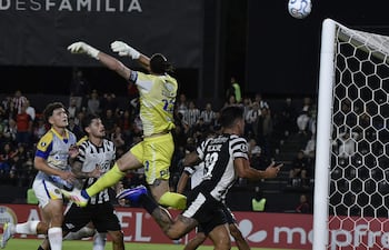 Jugadores de Libertad en camiseta blanca y Rosario Central en camiseta amarilla, en un campo de fútbol con un balón en el centro.