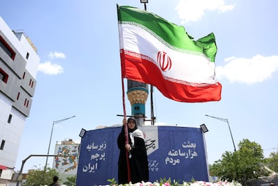 Una mujer con una bandera de Irán en una calle de Teherán.