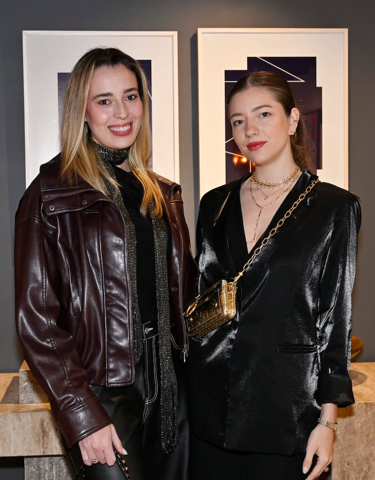 Mujeres sonrientes en chaquetas elegantes, de pie en un ambiente moderno y cálido.