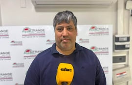 Adolfo Villalba, con cabello canoso y barba, sostiene un micrófono mientras habla frente a un cartel de 'SITRANDE'.
