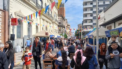 Una calle llena de familias, un niño con camiseta roja y un hombre que lleva a otro niño sobre sus hombros en un ambiente festivo.