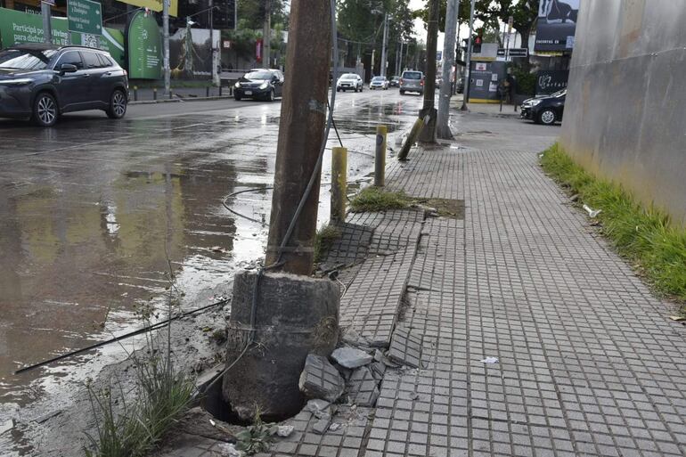 Escena urbana desolada con pavimento dañado y un poste de luz desestabilizado en la Avenida España.