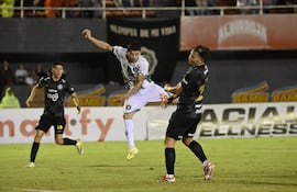 Fernando Martínez, futbolista de Rubio Ñu, remata el balón contra el rostro de Carlos Sebastián Ferreira (d), jugador de Olimpia, en el partido por la fecha 16 del torneo Apertura 2026 de la Primera División de Paraguay en el estadio Antonio Aranda, en Ciudad del Este, Paraguay.