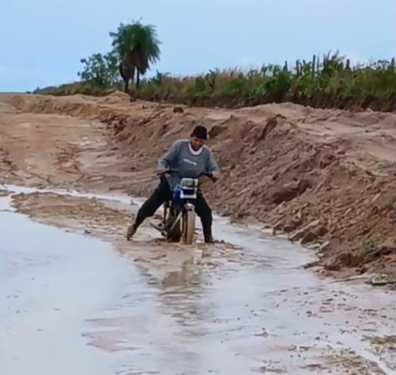 Un motociclista trata se cruzar un enorme charco formado en medio de un camino vecinal que conecta el distrito de Santanó con 25 de Diciembre