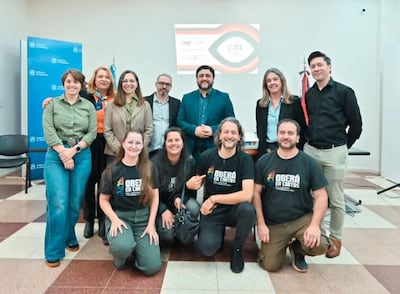 Grupo de diez personas, cinco de pie y cinco en cuclillas, con camisetas de 'OBERÁ EN CORTOS' y fondo institucional.